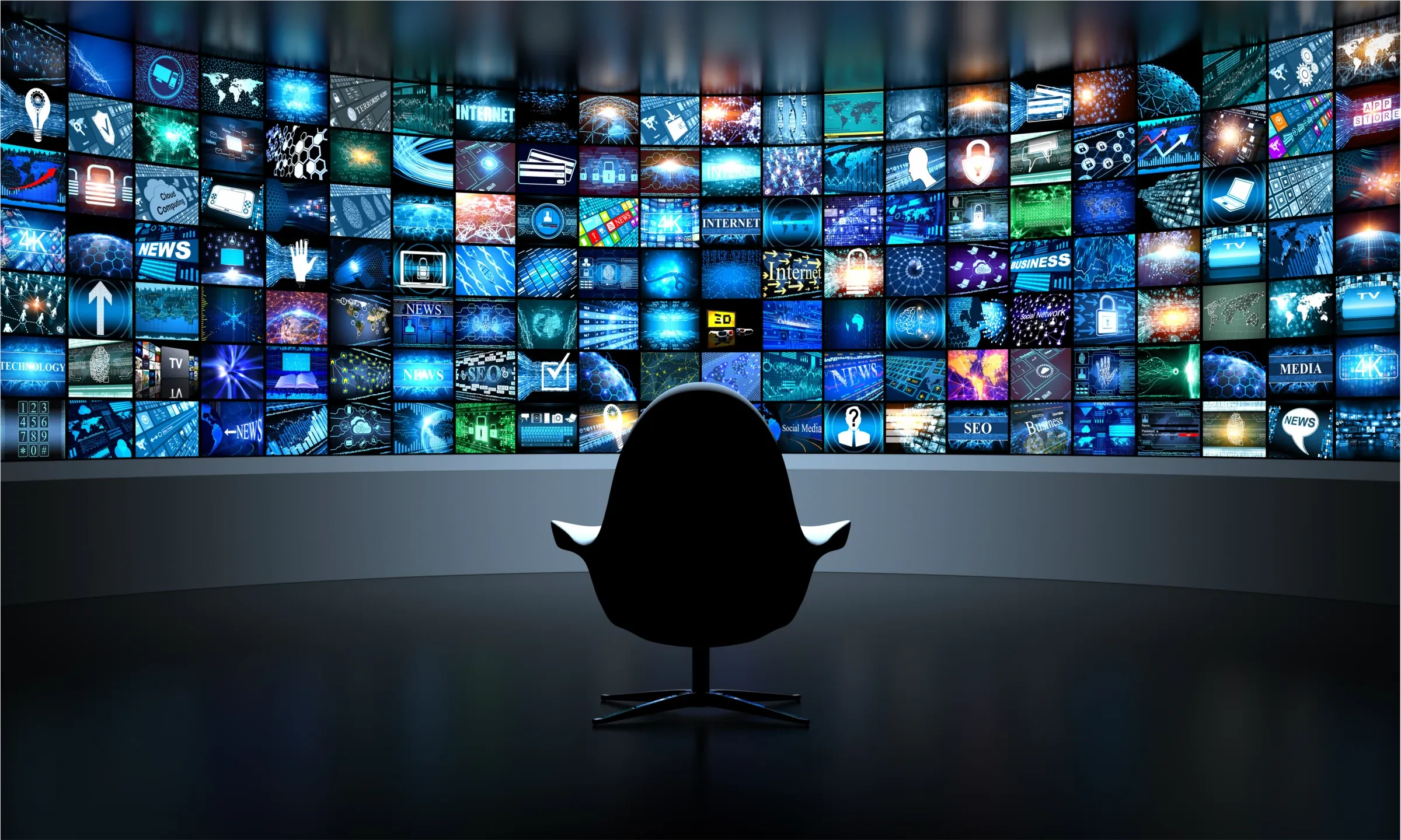 A curved wall of screens playing news, technology and business footage, facing a single empty chair